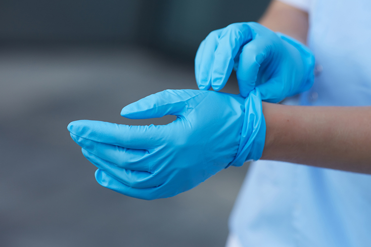 healthcare worker putting on latex gloves