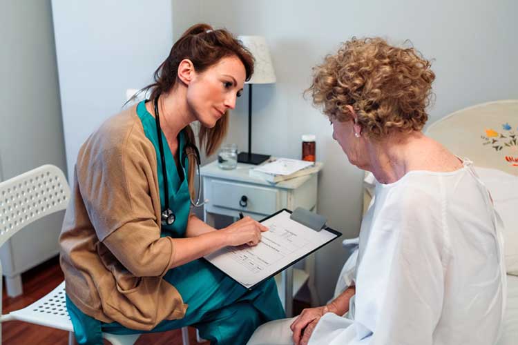 Female nurse providing an update to her elderly female patient