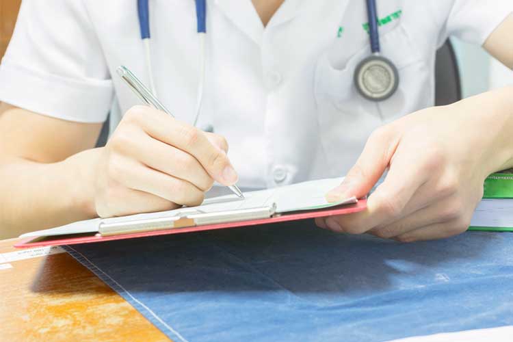 Health professional taking down notes on a clipboard | Image