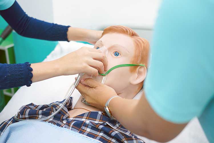 Two nurses practicing using an oxygen mask on a dummy