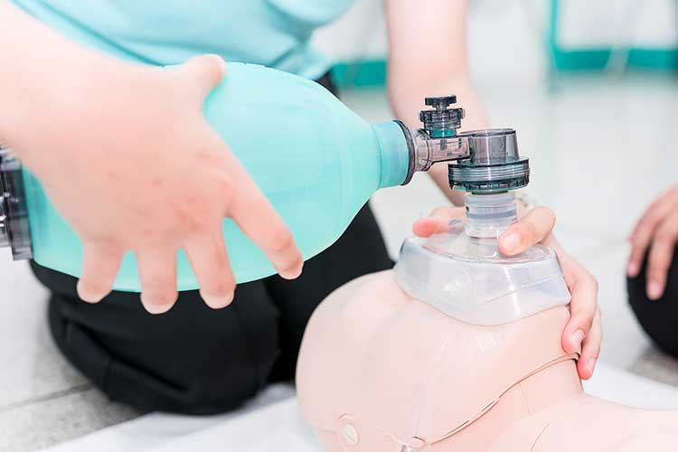 Woman performing manual ventilation with a bag-valve-mask on a dummy