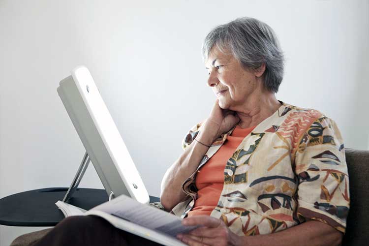 woman undergoing light therapy whilst reading a book