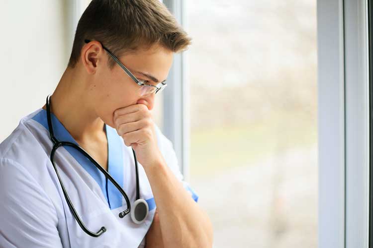 Concerned male nurse pondering out of a window