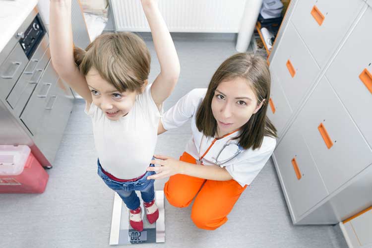 Nurse checking the weight of a child