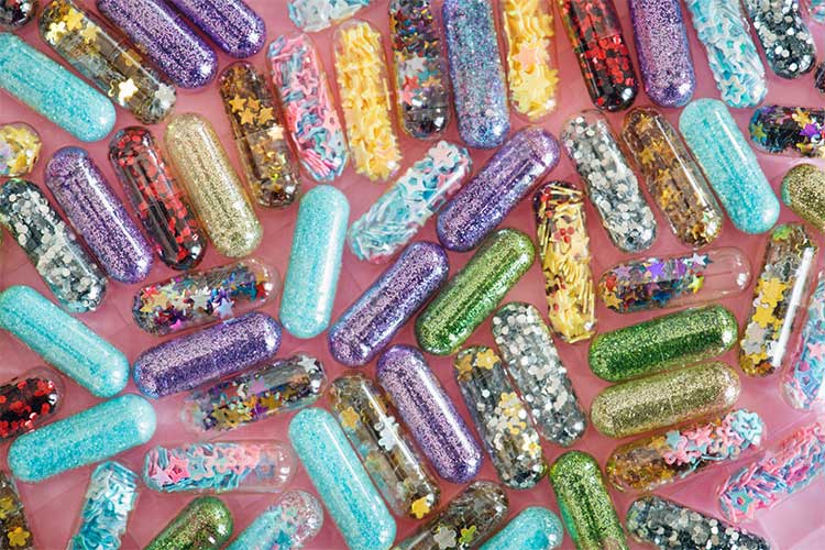 Scattered pills with glitter enclosed within