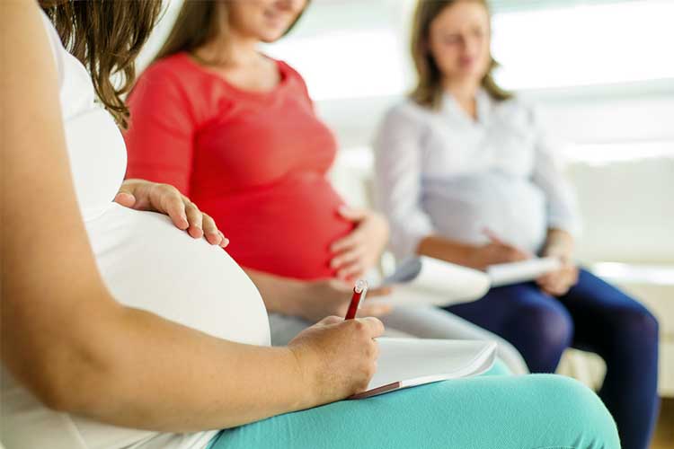 Three pregnant women taking notes at a counselling session
