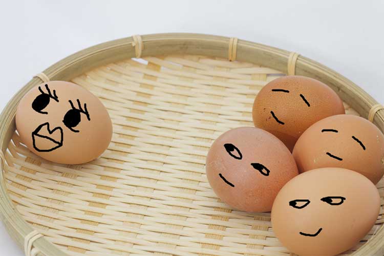 Concept of tall poppy syndrome using eggs in a basket with faces drawn on them